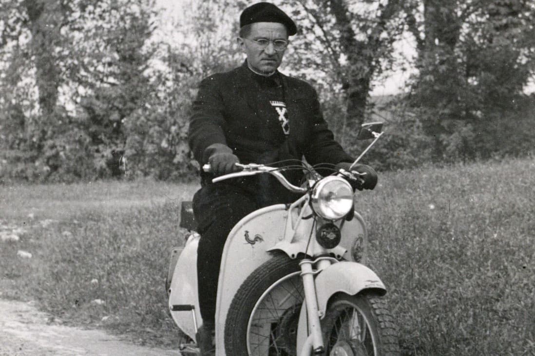 Un gesuita a bordo di una motocicletta su una strada di campagna - Archivio Storico - Gesuiti, Provincia Euro-Mediterranea